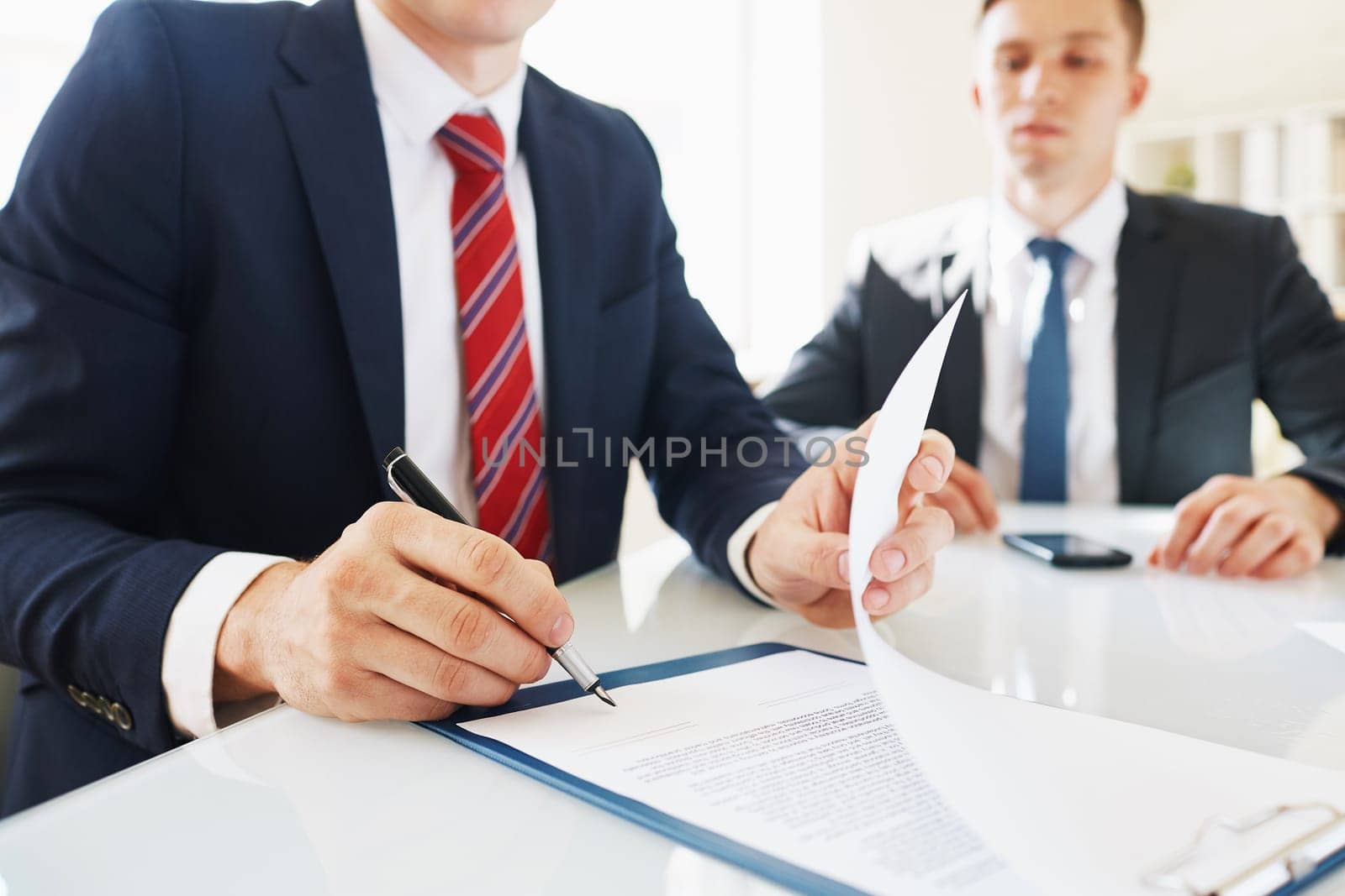Businessman signing contract with his partner near by