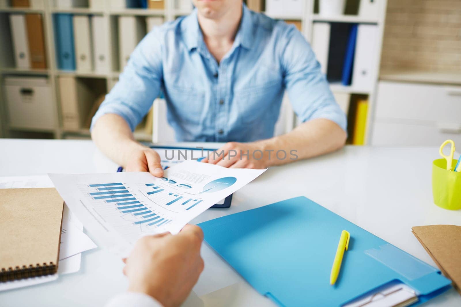 Male employee giving document with data to colleague