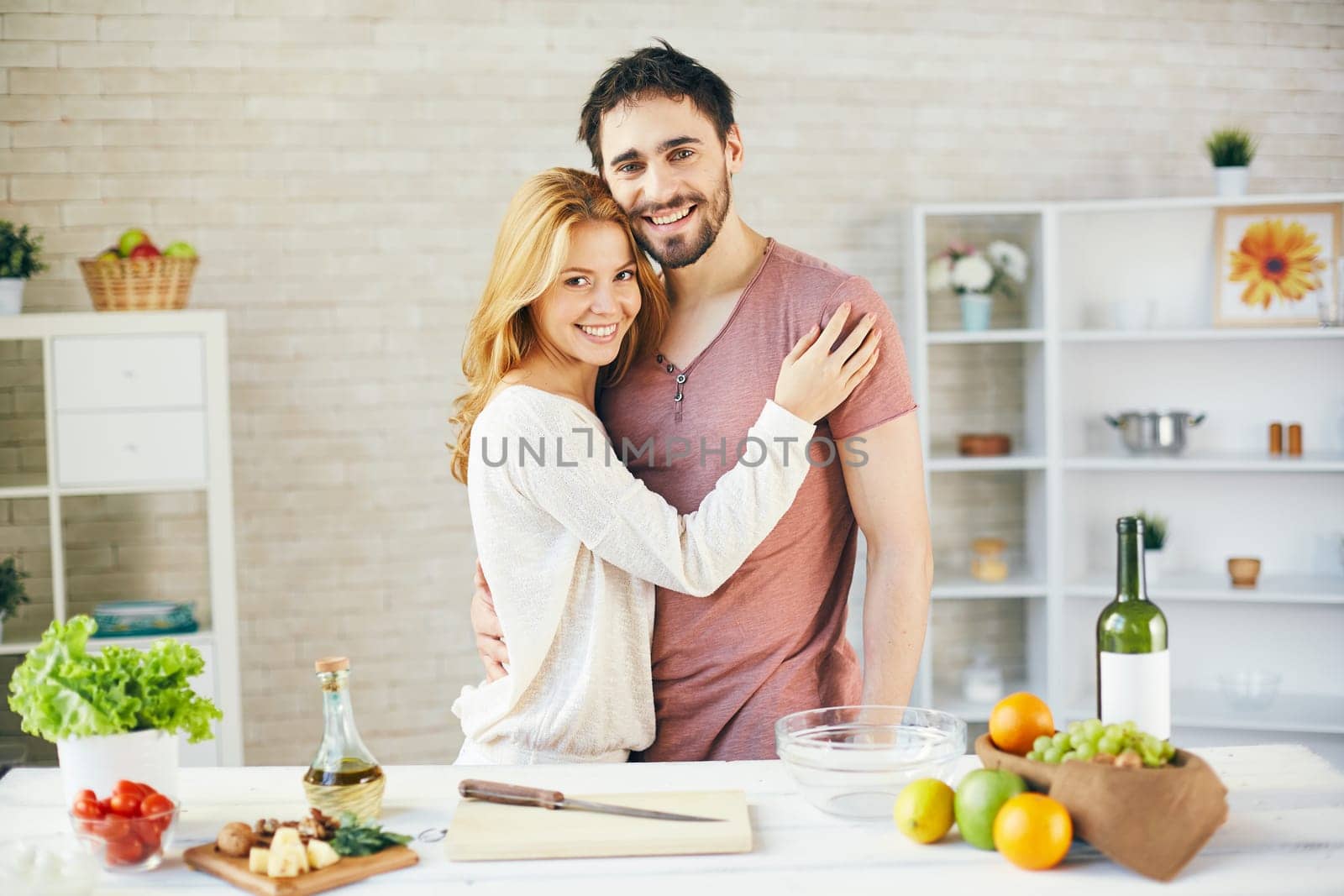 Happy young couple looking at camera in the kitchen
