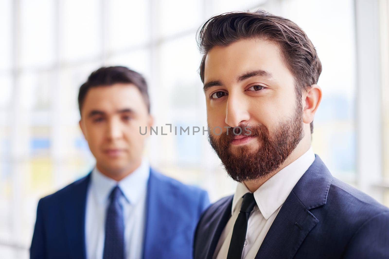 Confident businessman looking at camera on background of his colleague