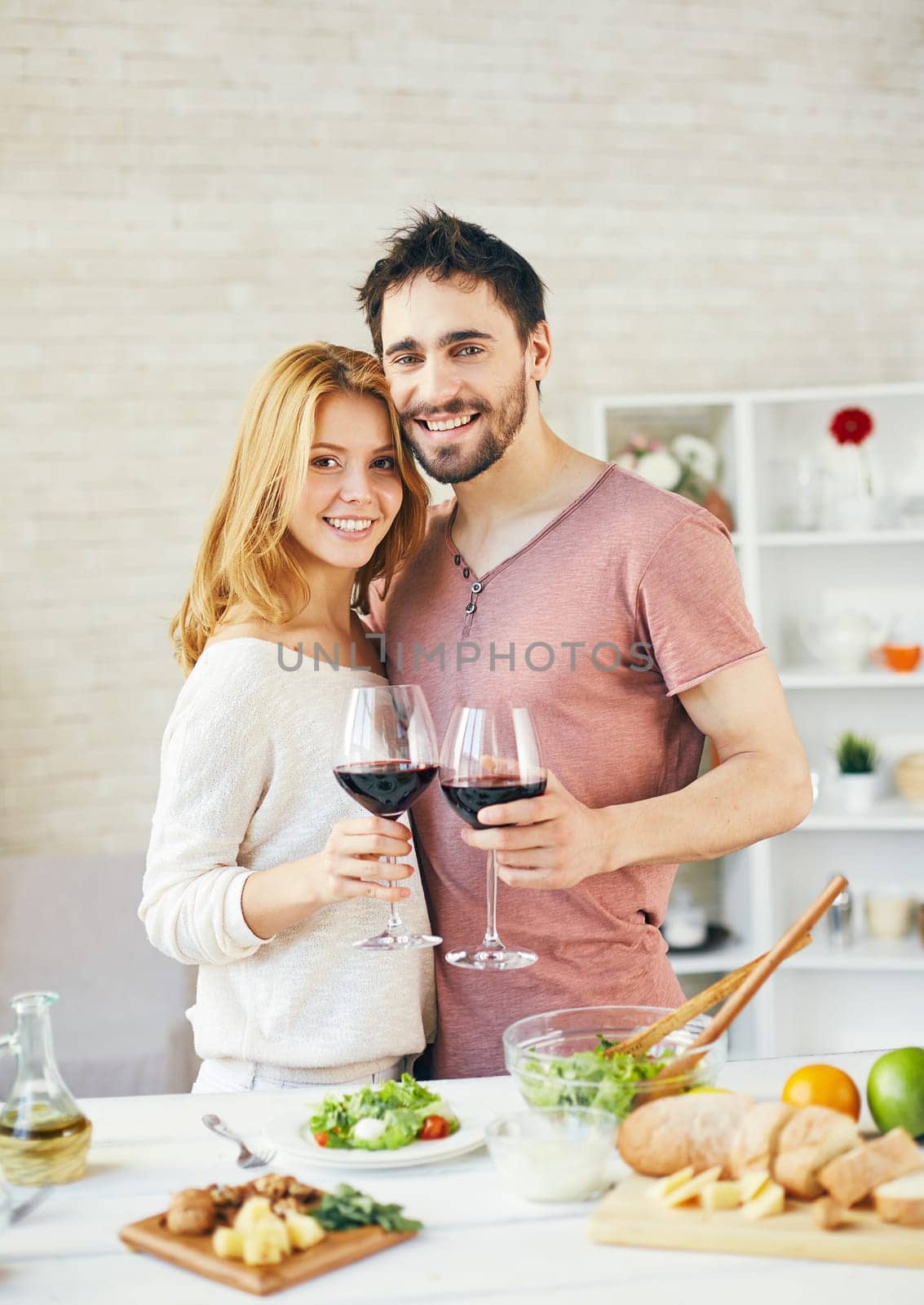 Amorous man and woman toasting with red wine in the kitchen
