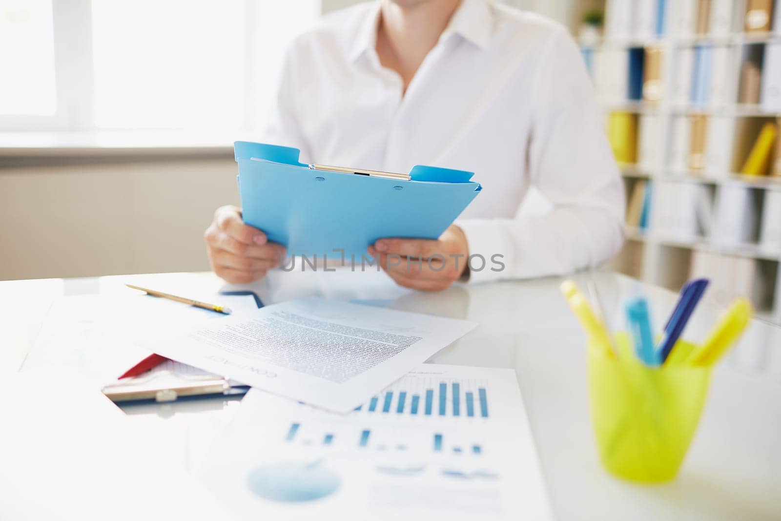 Male employee with clipboard sitting at workplace