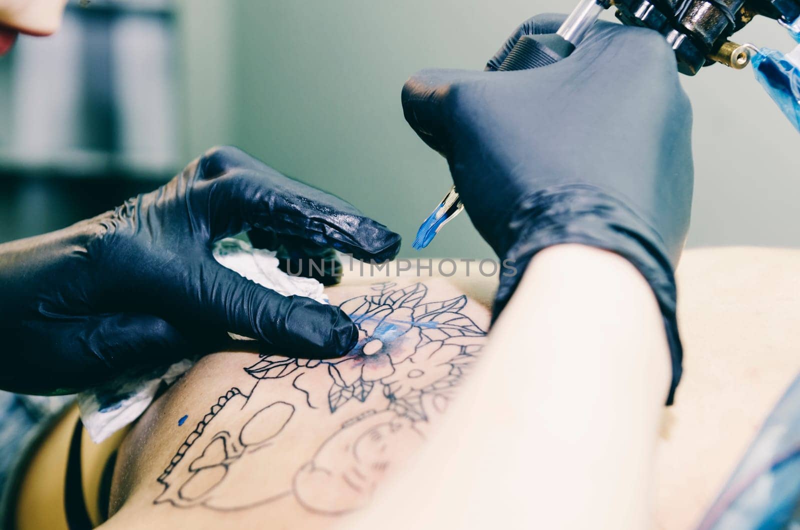 Closeup of tattoo artist tattooing young hipster woman in studio.