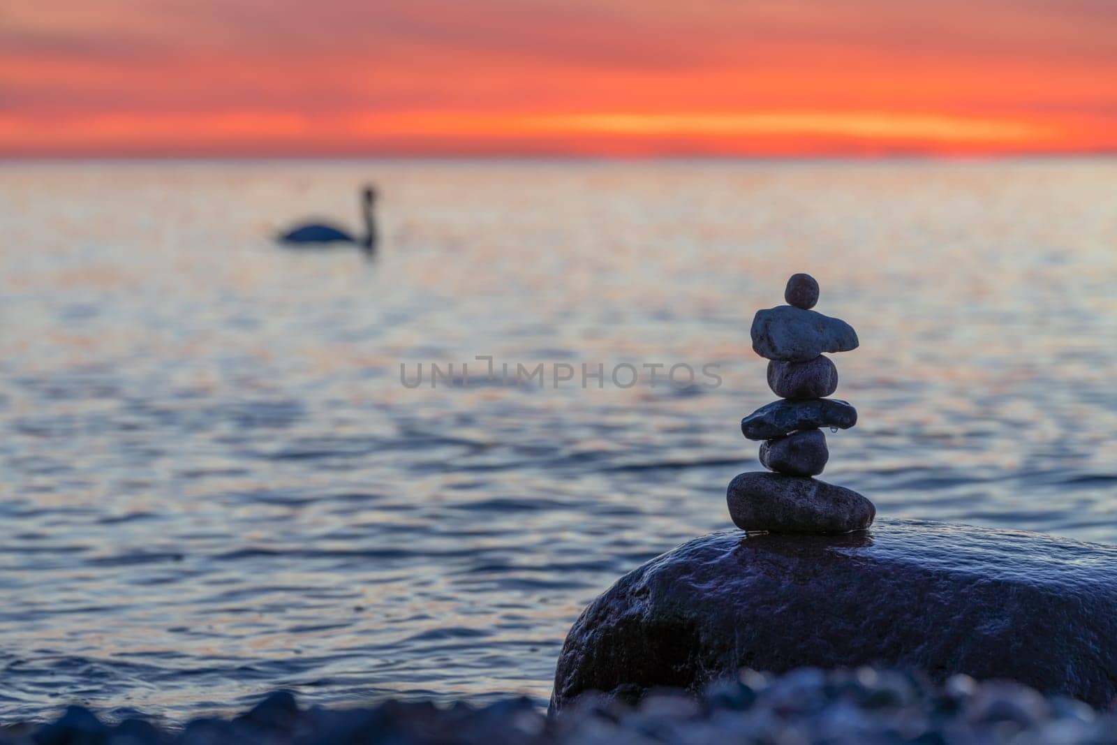 Stone pyramids on the dreamy Baltic Sea sandy beach on Rügen to the spectacular orange sunset