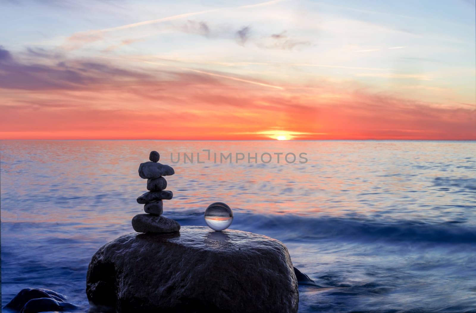 Stone pyramids and glass sphere on the dreamy Baltic Sea sand beach on Rügen to the spectacular orange sunset