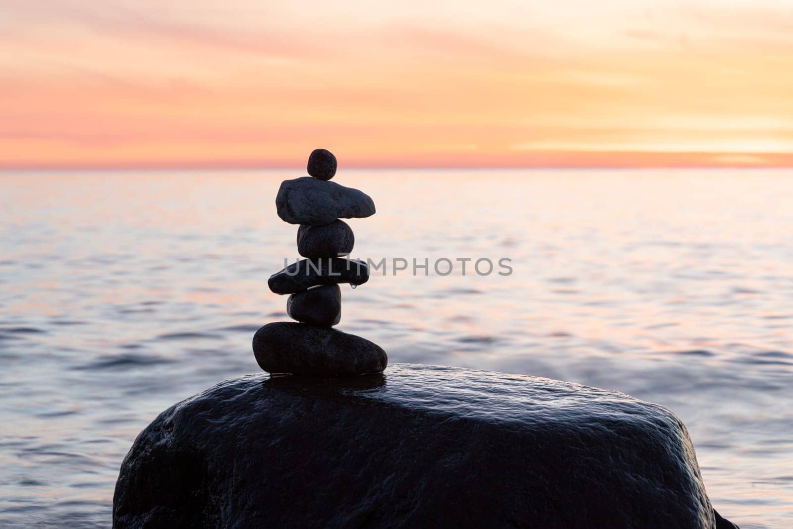 Stone pyramids on the dreamy Baltic Sea sandy beach on Rügen to the spectacular orange sunset