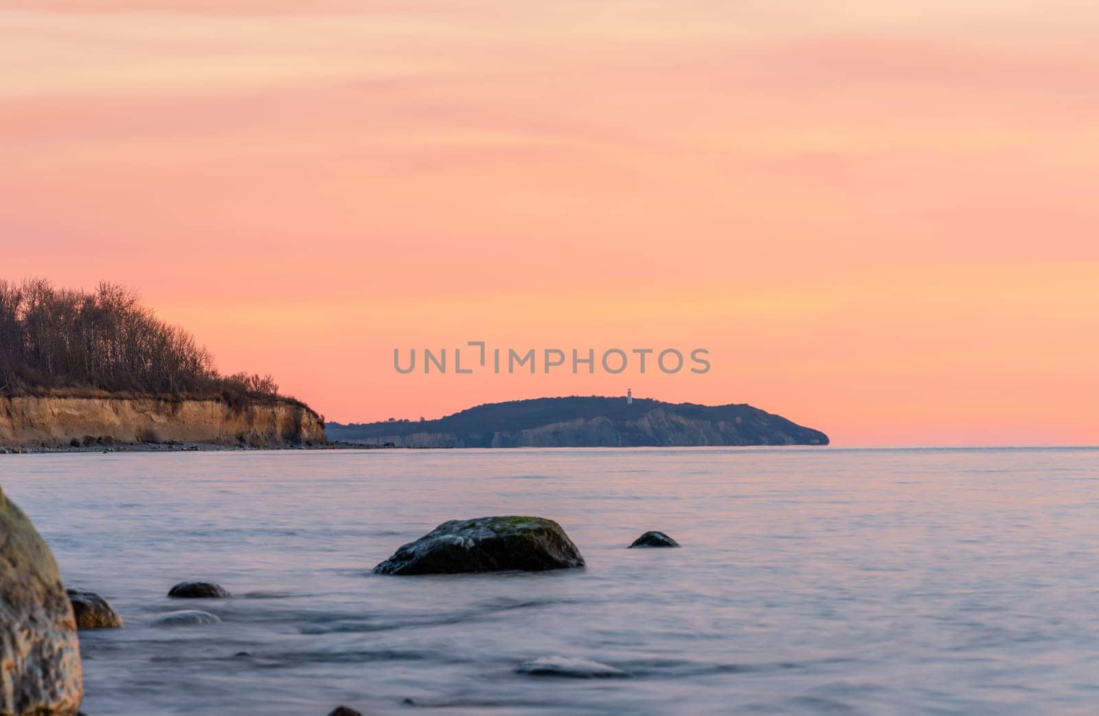magnificent Baltic Sea coast on the island of Rügen with a view of Hiddensee to the orange sunset