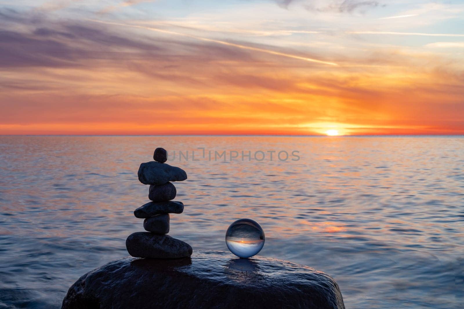 Stone pyramids and glass sphere on the dreamy Baltic Sea sand beach on Rügen to the spectacular orange sunset