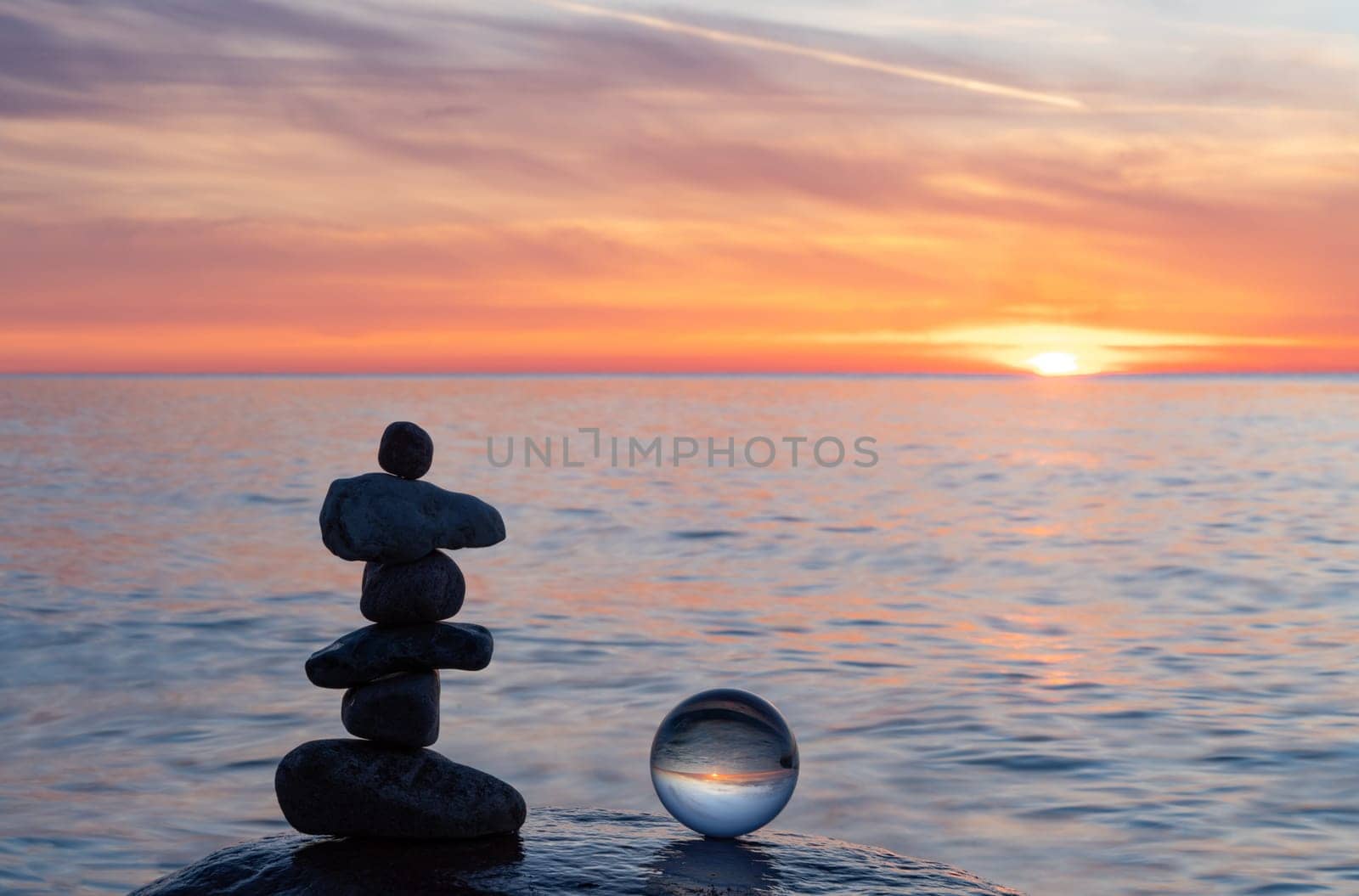 Stone pyramids and glass sphere on the dreamy Baltic Sea sand beach on Rügen to the spectacular orange sunset