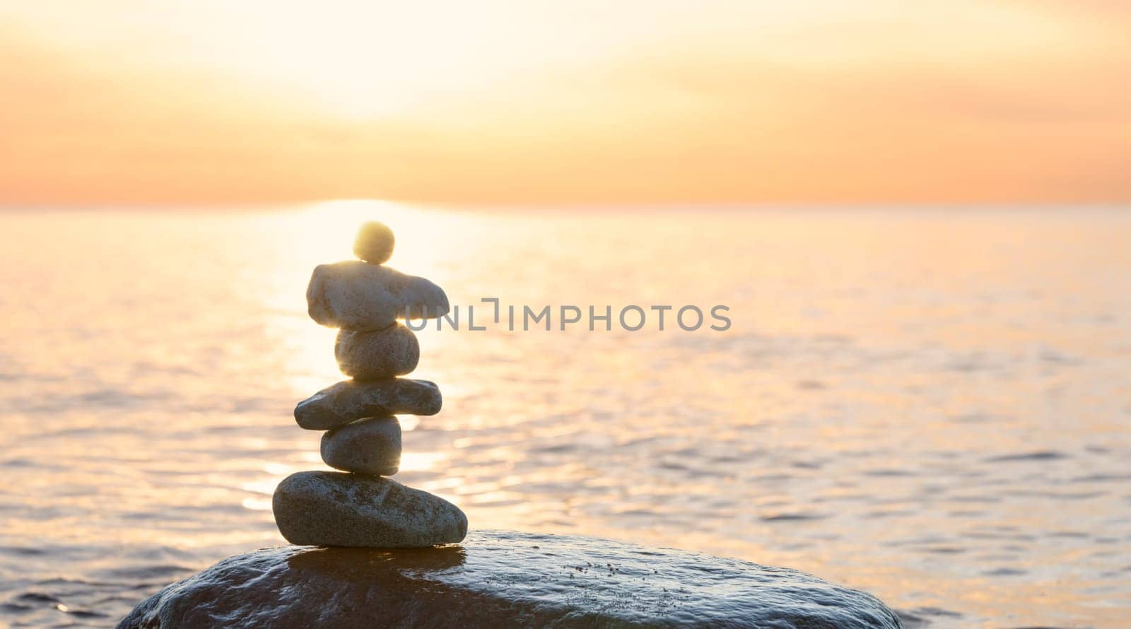 Stone pyramids on the dreamy Baltic Sea sandy beach on Rügen to the spectacular orange sunset