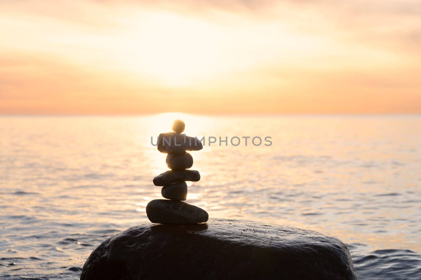 Stone pyramids on the dreamy Baltic Sea sandy beach on Rügen to the spectacular orange sunset