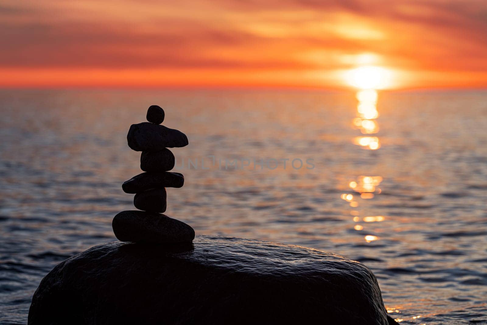 Stone pyramids on the dreamy Baltic Sea sandy beach on Rügen to the spectacular orange sunset