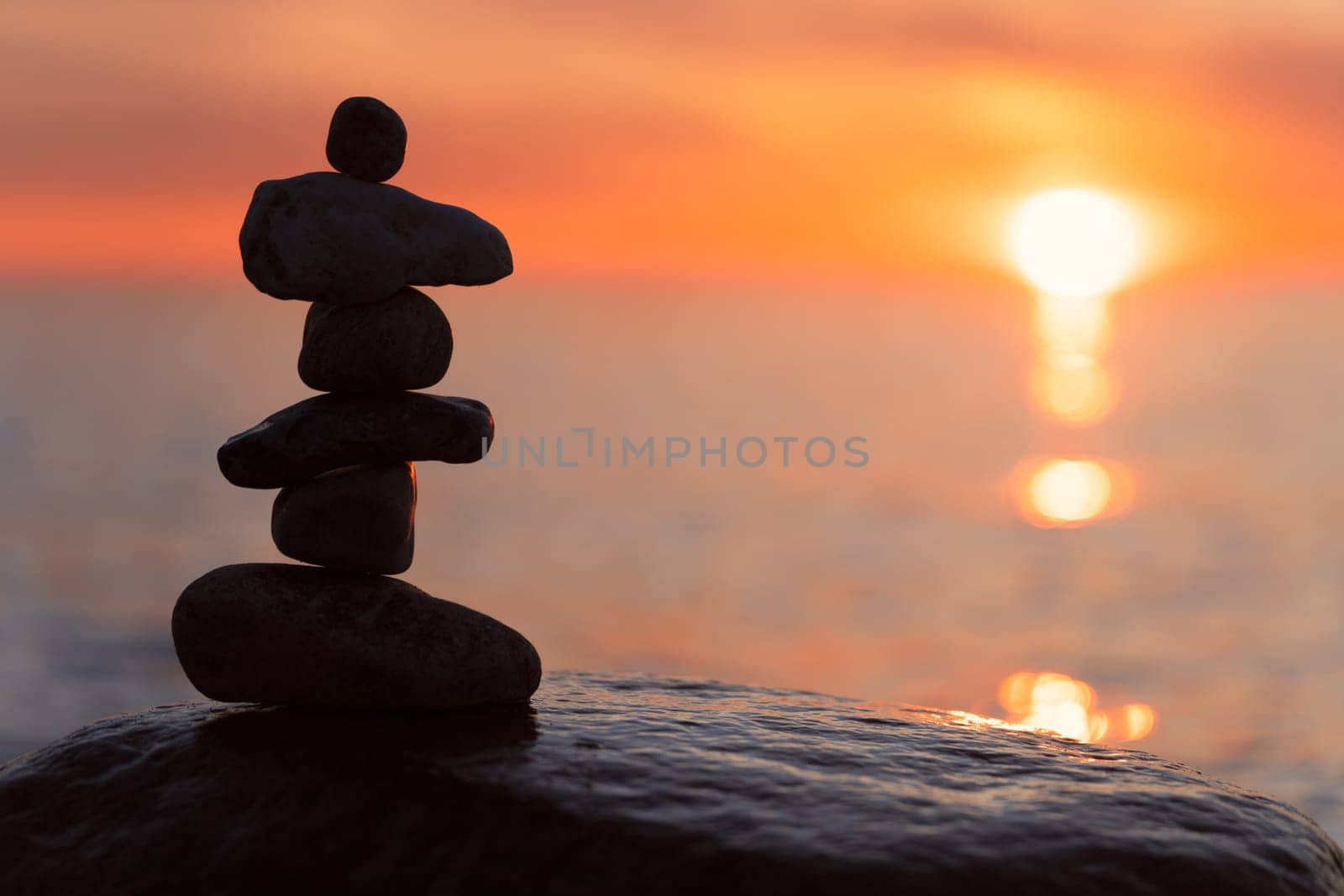 Stone pyramids on the dreamy Baltic Sea sandy beach on Rügen to the spectacular orange sunset