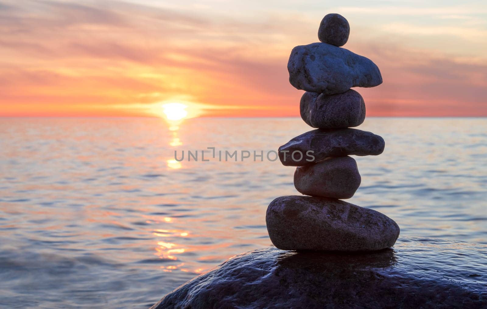Stone pyramids on the dreamy Baltic Sea sandy beach on Rügen to the spectacular orange sunset