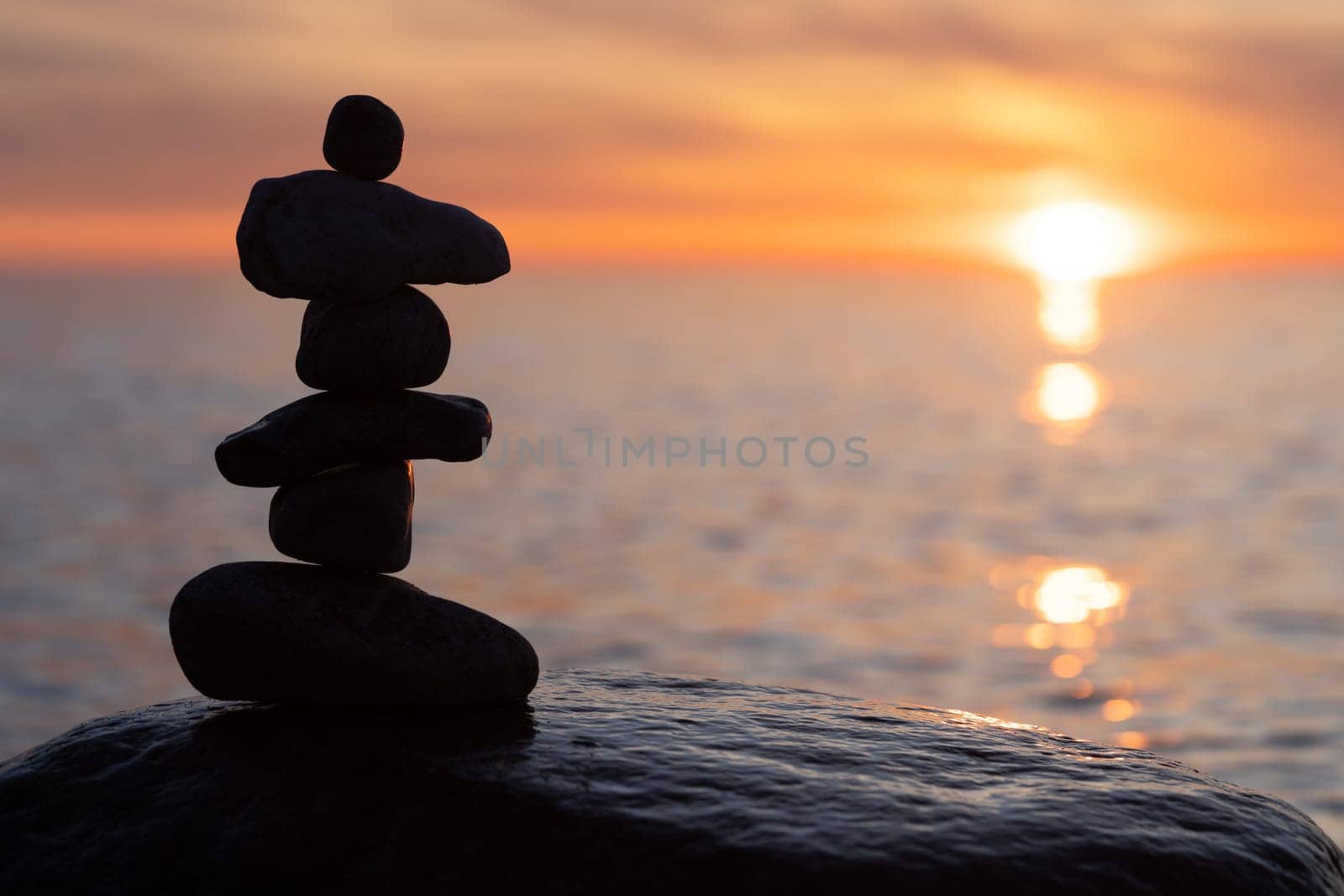 Stone pyramids on the dreamy Baltic Sea sandy beach on Rügen to the spectacular orange sunset