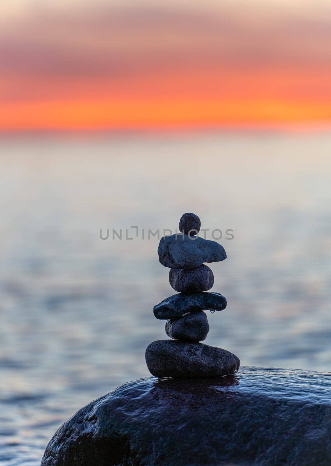 Stone pyramids on the dreamy Baltic Sea sandy beach on Rügen to the spectacular orange sunset