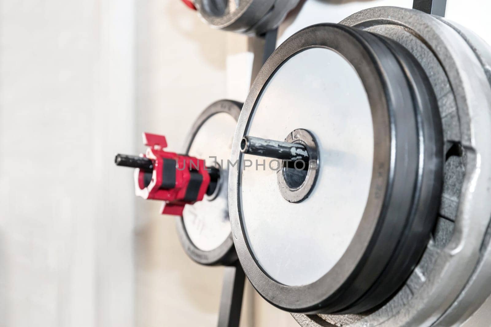 Modern lightweight gymnasium. Sports equipment in the gym. Barbells of different weights on racks. Copy space.