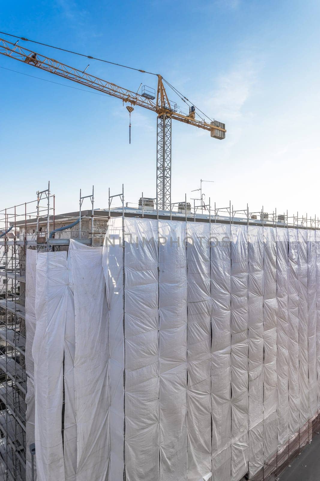Extensive scaffolding providing platforms for work in progress on a new apartment block, Tall building under construction with scaffolding, New construction site.