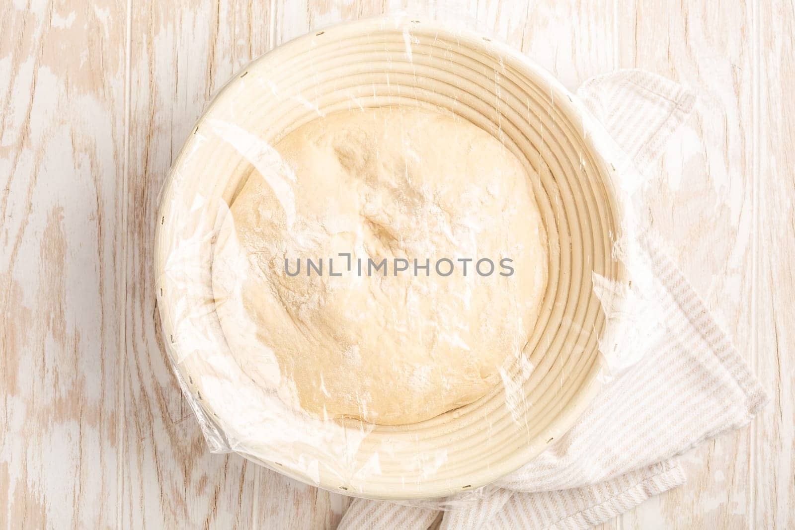 Raw yeast dough resting and rising in a special basket on kitchen table