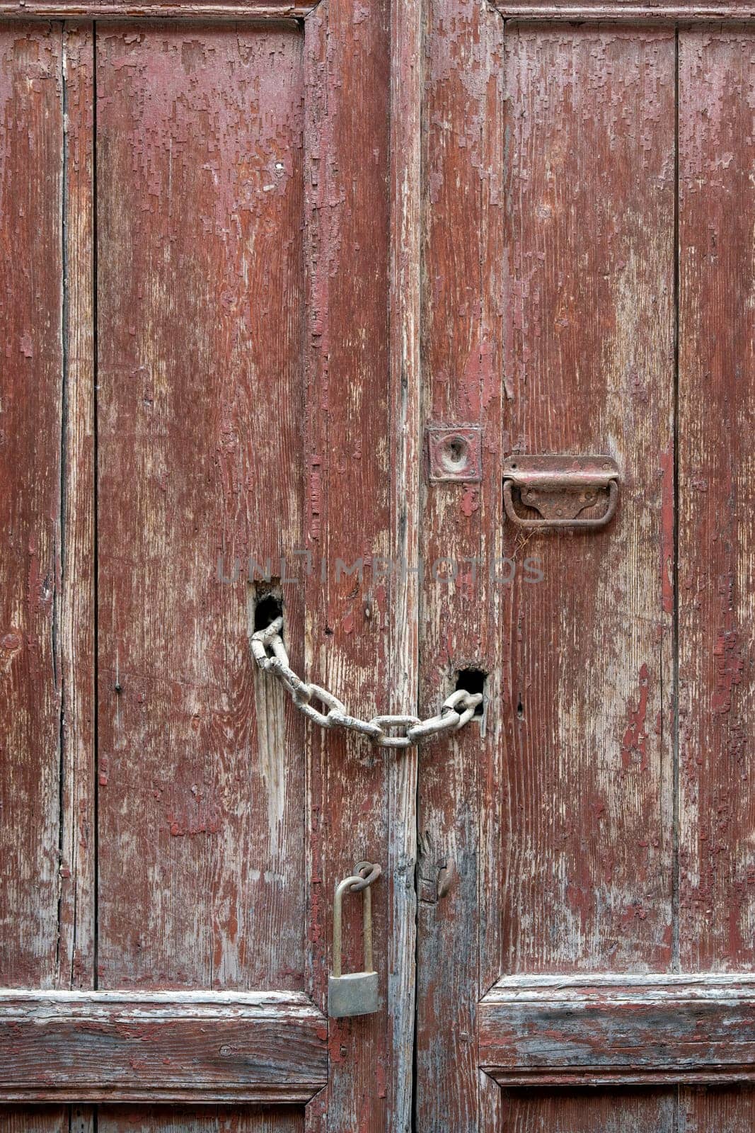 Old rough wooden door with bolts and padlocks. Details of iron and wood.