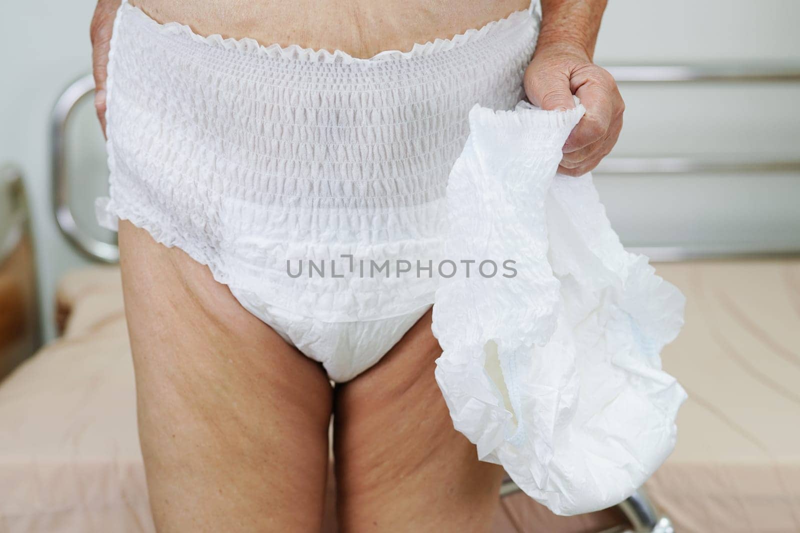 Asian elder senior woman patient wearing adult incontinence diaper pad in hospital.