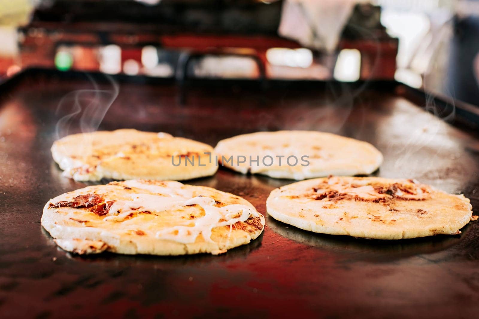 Traditional Salvadoran pupusas with melted cheese on a grill, Traditional cheese pupusas on the grill. Side view of four traditional crispy pupusas on the grill