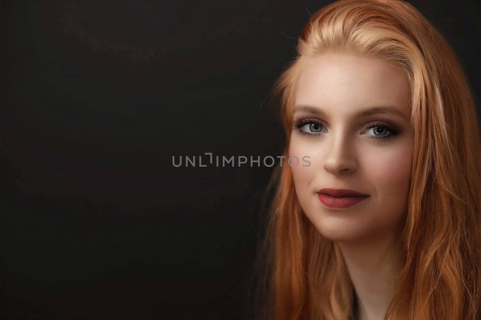Portrait of smiling redhead young woman with red lips  on the black background.