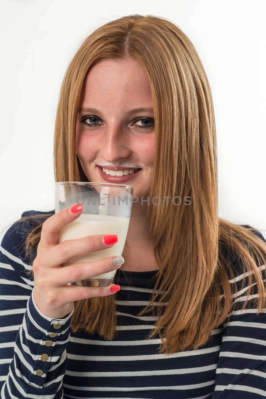 Smiling young girl drinking a glass of milk on a white background