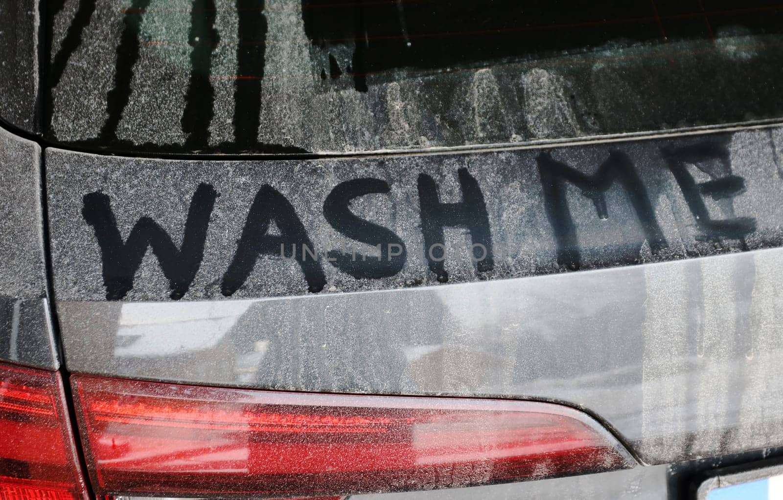 A dirty black car says wash me