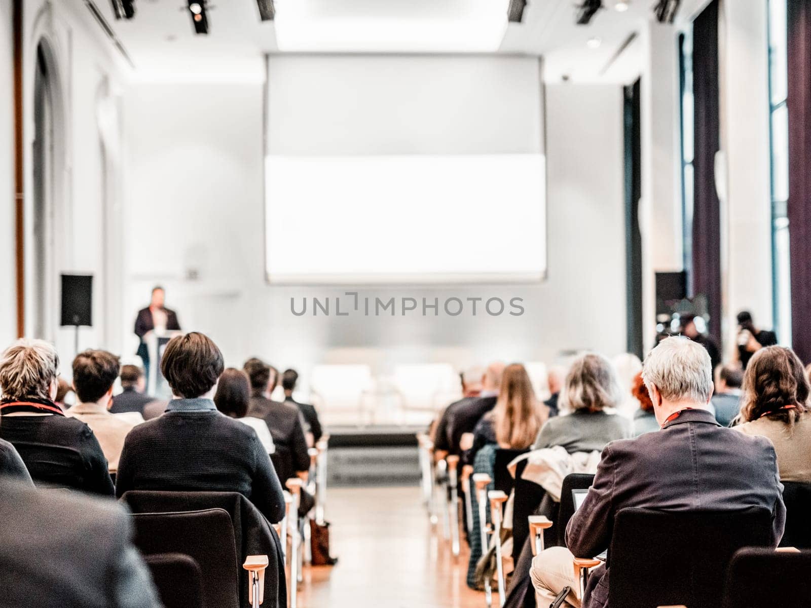 Speaker giving a talk in conference hall at business event. Rear view of unrecognizable people in audience at the conference hall. Business and entrepreneurship concept