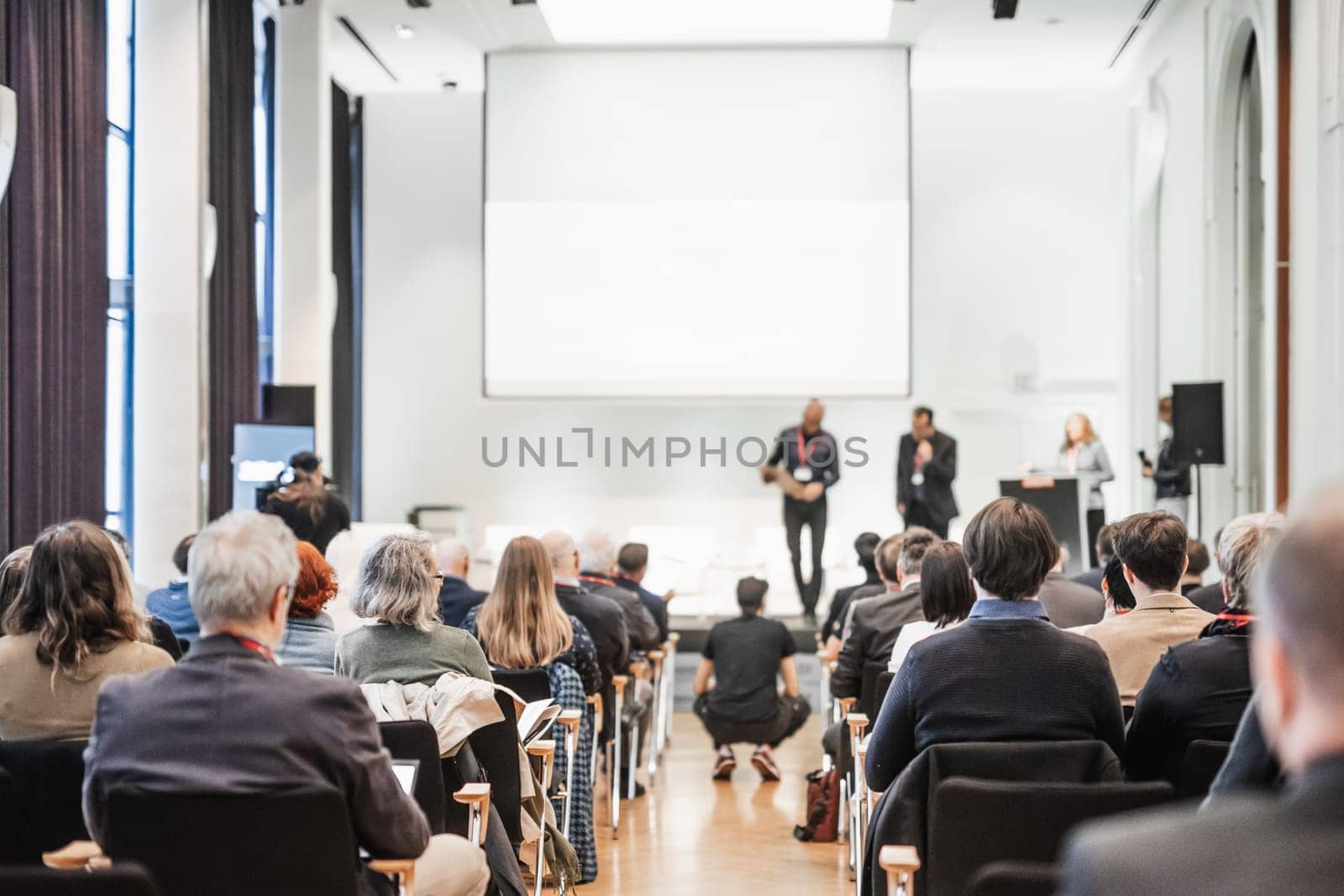Business team leader receiving award prize at best business project competition event. Business and entrepreneurship award ceremony theme. Focus on unrecognizable people in audience