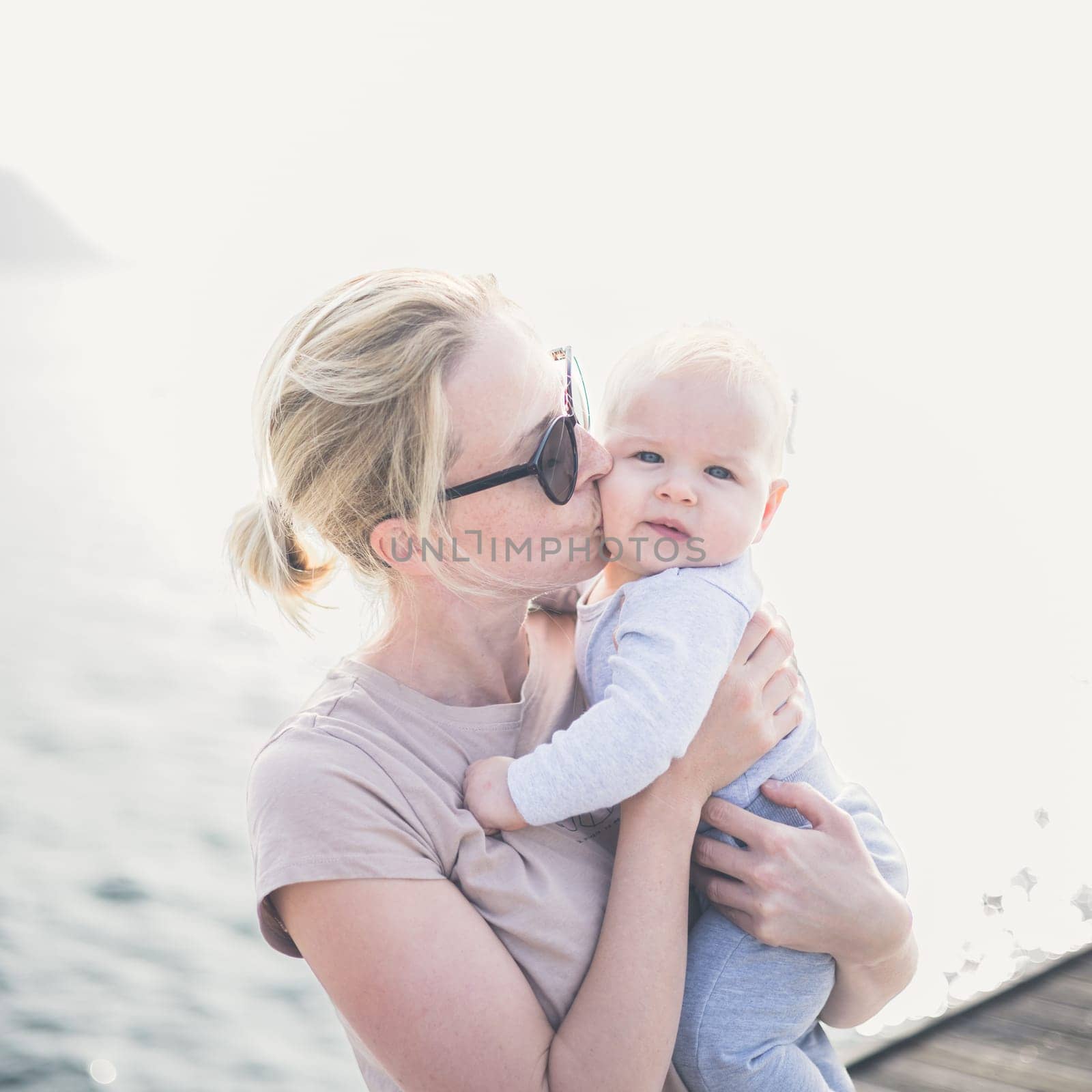 Tender woman caressing her little baby boy infant child outdoors. Mother's unconditional love for her child.