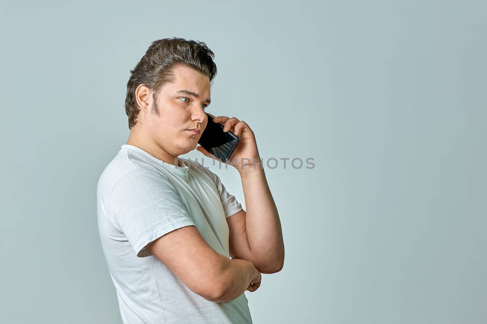 a man on a gray background is talking on the phone. High quality photo