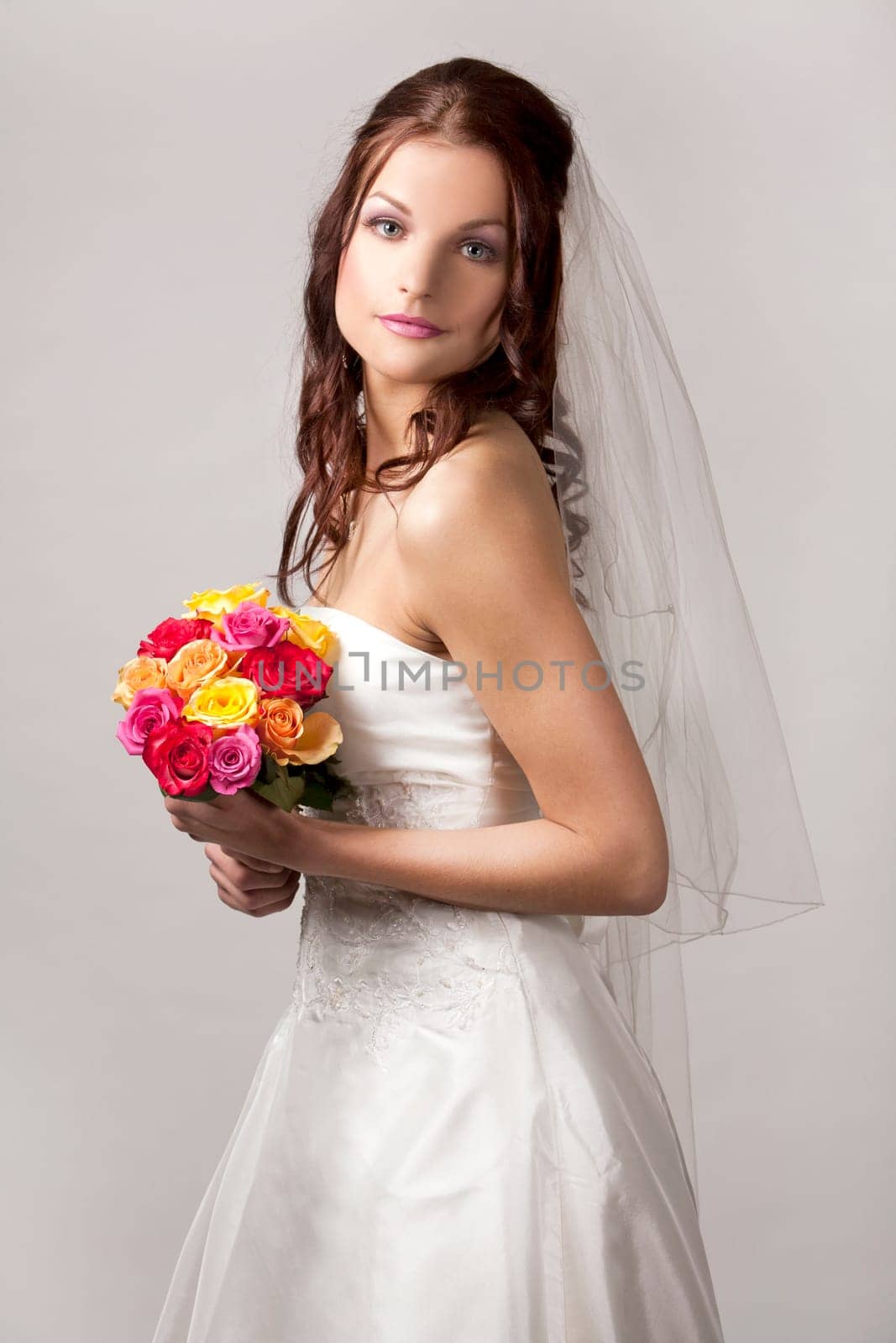pretty brunette wearing wedding dress on light background