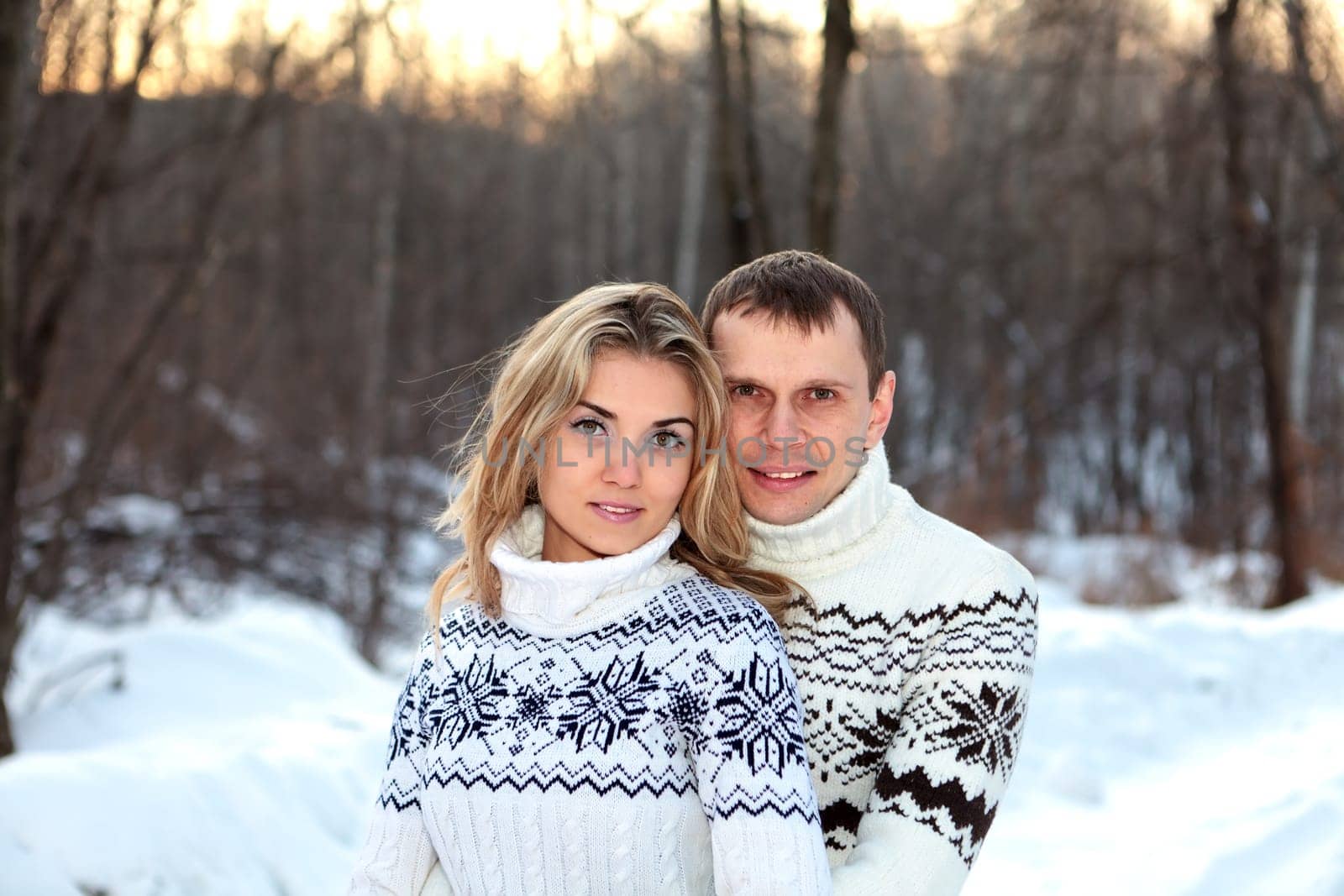 Happy pair in winter forest dressed in sweater