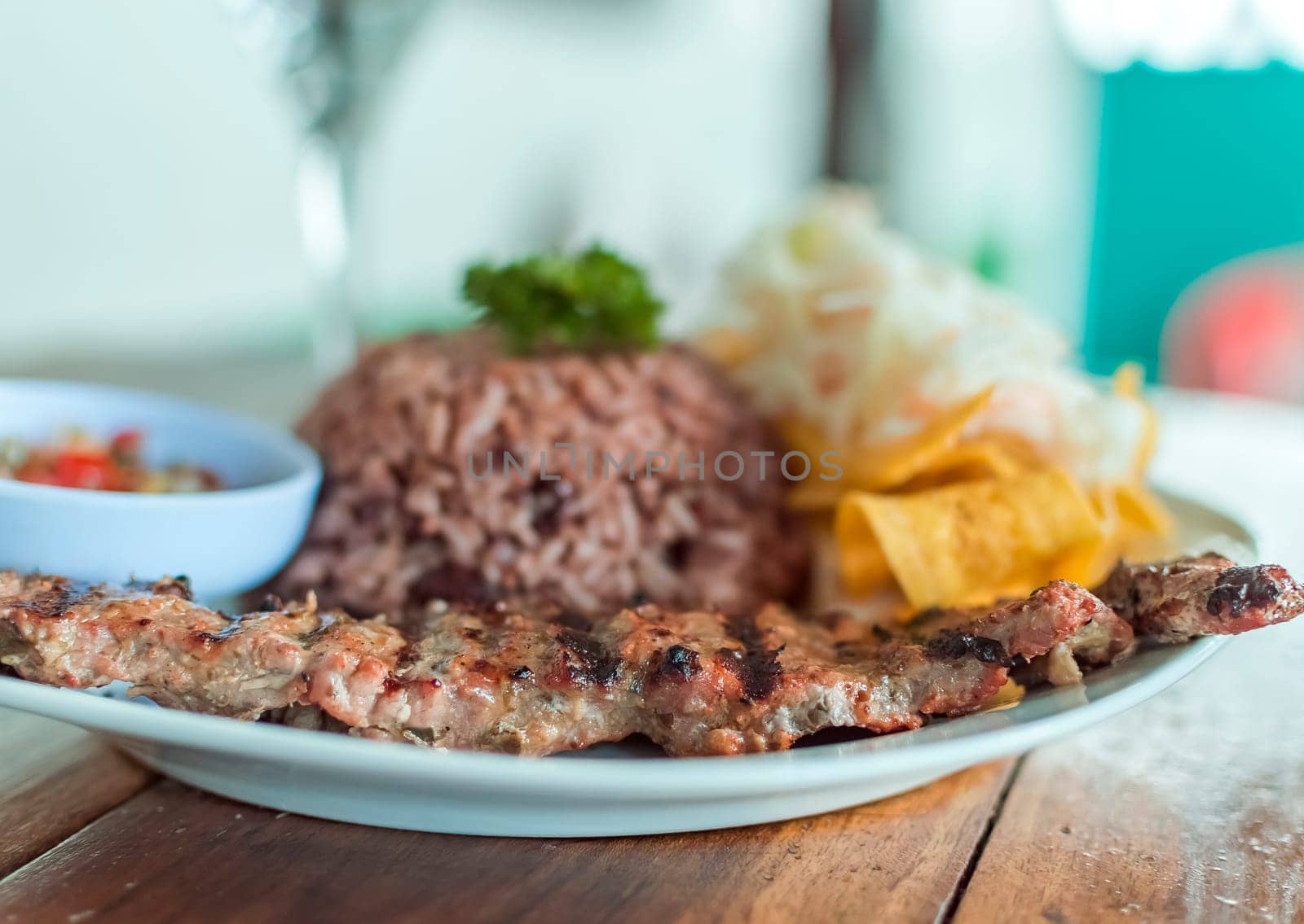 Close up of roast beef with gallo pinto and pico de gallo, Nicaraguan food served on wooden table, Plate with roast beef and rice served on wooden table