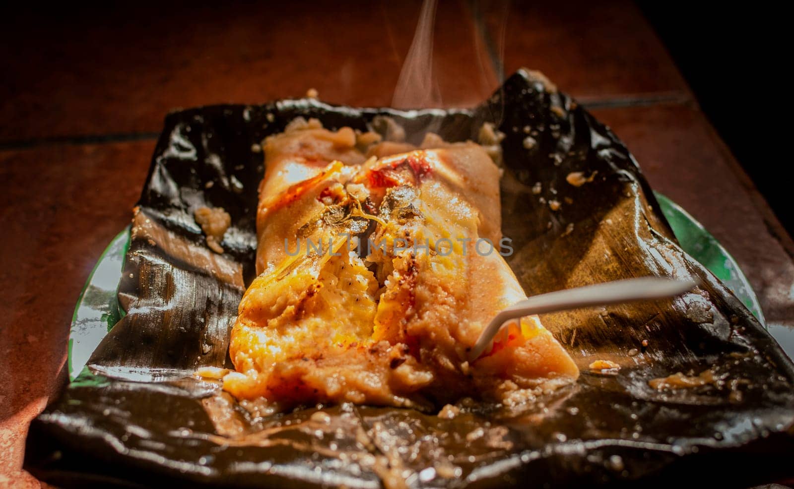 Traditional Nacatamal served in banana leaf, Close up of Nicaraguan Nacatamal ready to eat, Typical Nicaraguan Nacatamal freshly made served on the table. Homemade Nicaraguan Nacatamal