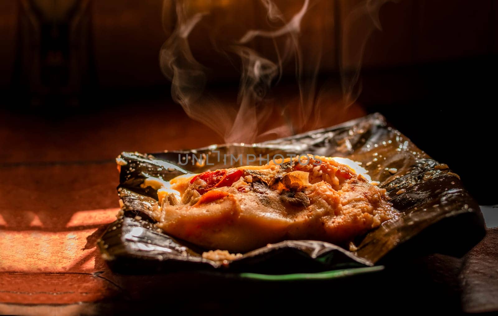 Side view of Nicaraguan Nacatamal ready to eat, Typical Nicaraguan Nacatamal freshly made served on the table, Homemade Nicaraguan Nacatamal, Traditional Nacatamal served in banana leaf
