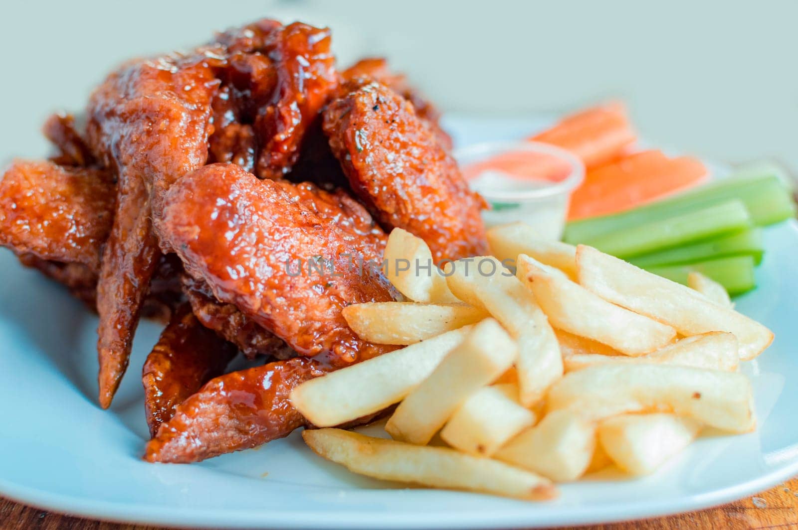 Plate of barbecue wings and fries with ranch sauce, Close up of plate of hot wings and fries served on the table. National typical food concept