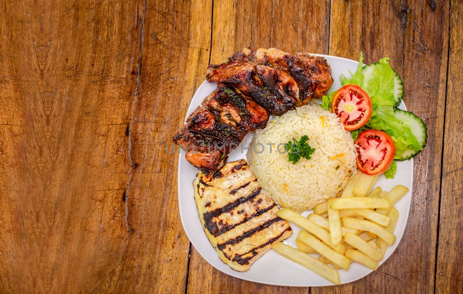 Top view of plate of fresh Pork rib served on the table. Pork rib with rice, fried cheese and salad served on the table, Close up of Pork rib with salad and French fries served on wooden table