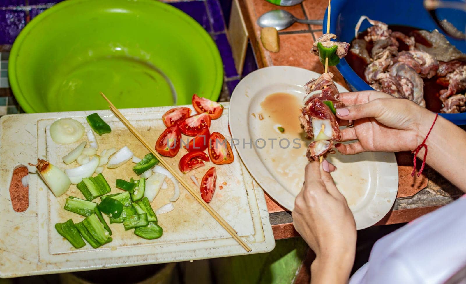 A person preparing roast beef skewers, close up of hands preparing meat skewers