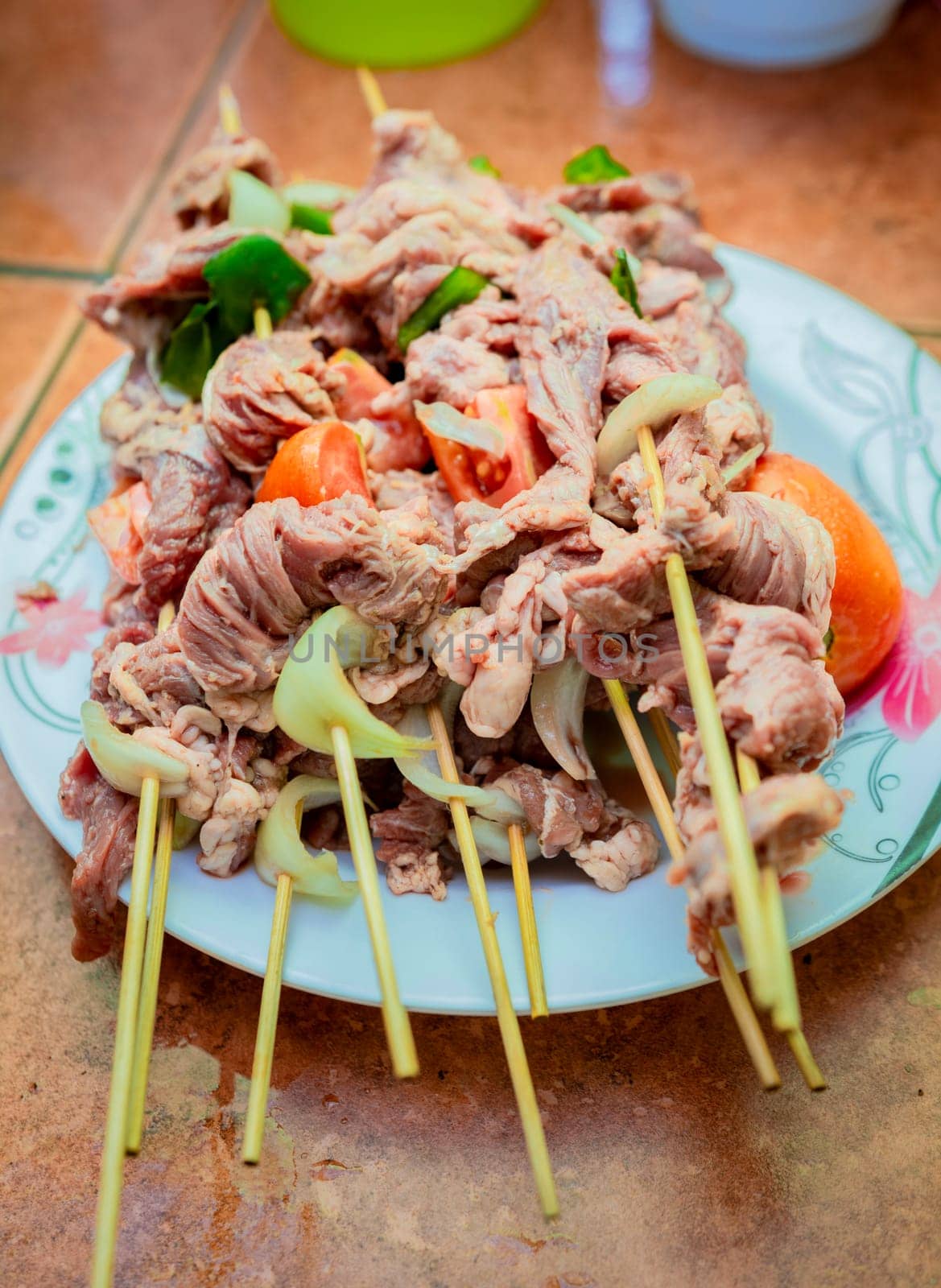 Raw beef skewers on a plate. Close up of raw beef meat skewers with ingredients. Fresh and raw beef skewers on a plate. Preparation of raw beef skewers.