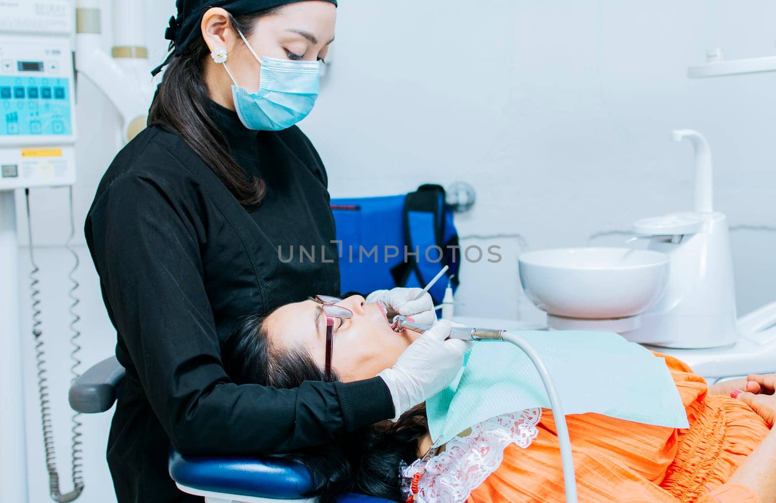 The stomatologist cleaning a patient's teeth, a dentist cleaning a patient's mouth, a dentist cleaning a patient's caries, a dentist cleaning a patient's mouth