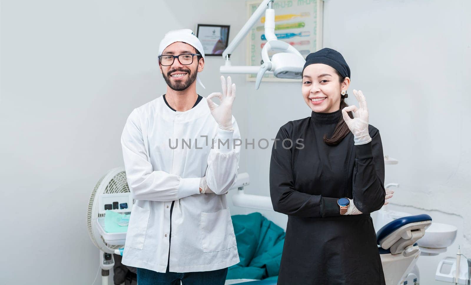 Portrait of dentist and her assistant in the office, female dentist and her assistant thumbs up, oral professionals portrait