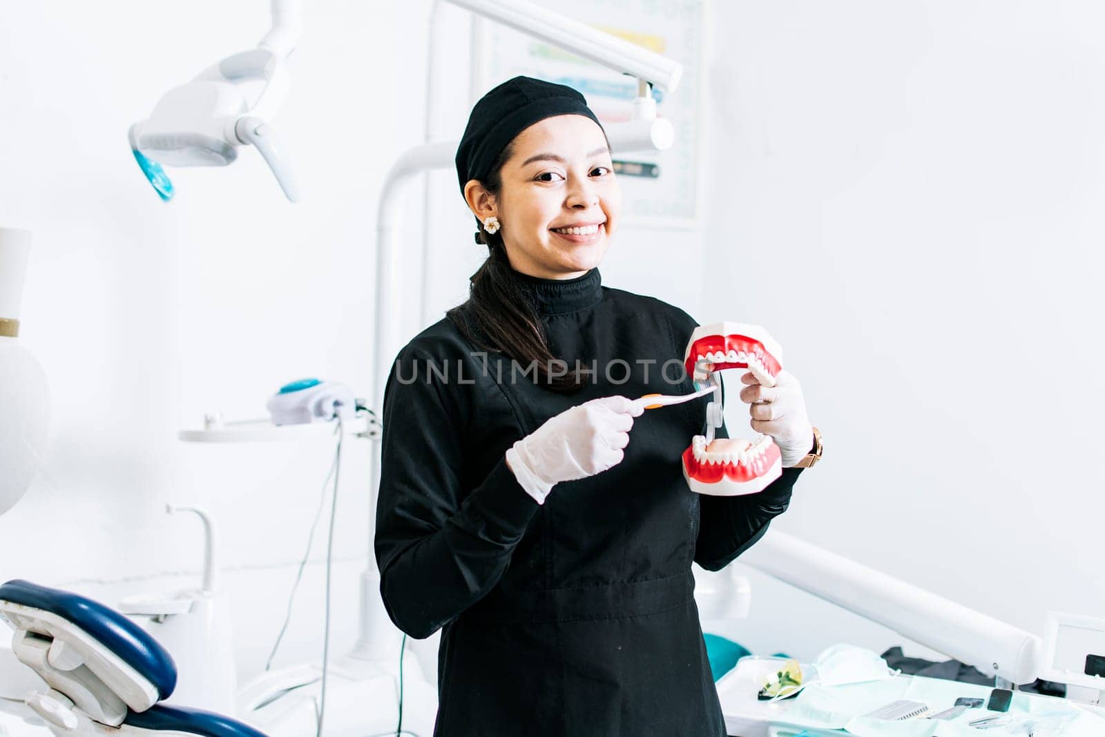 Smiling female dentist showing a denture, Dentist explaining tooth brushing, female dentist showing a denture and brush