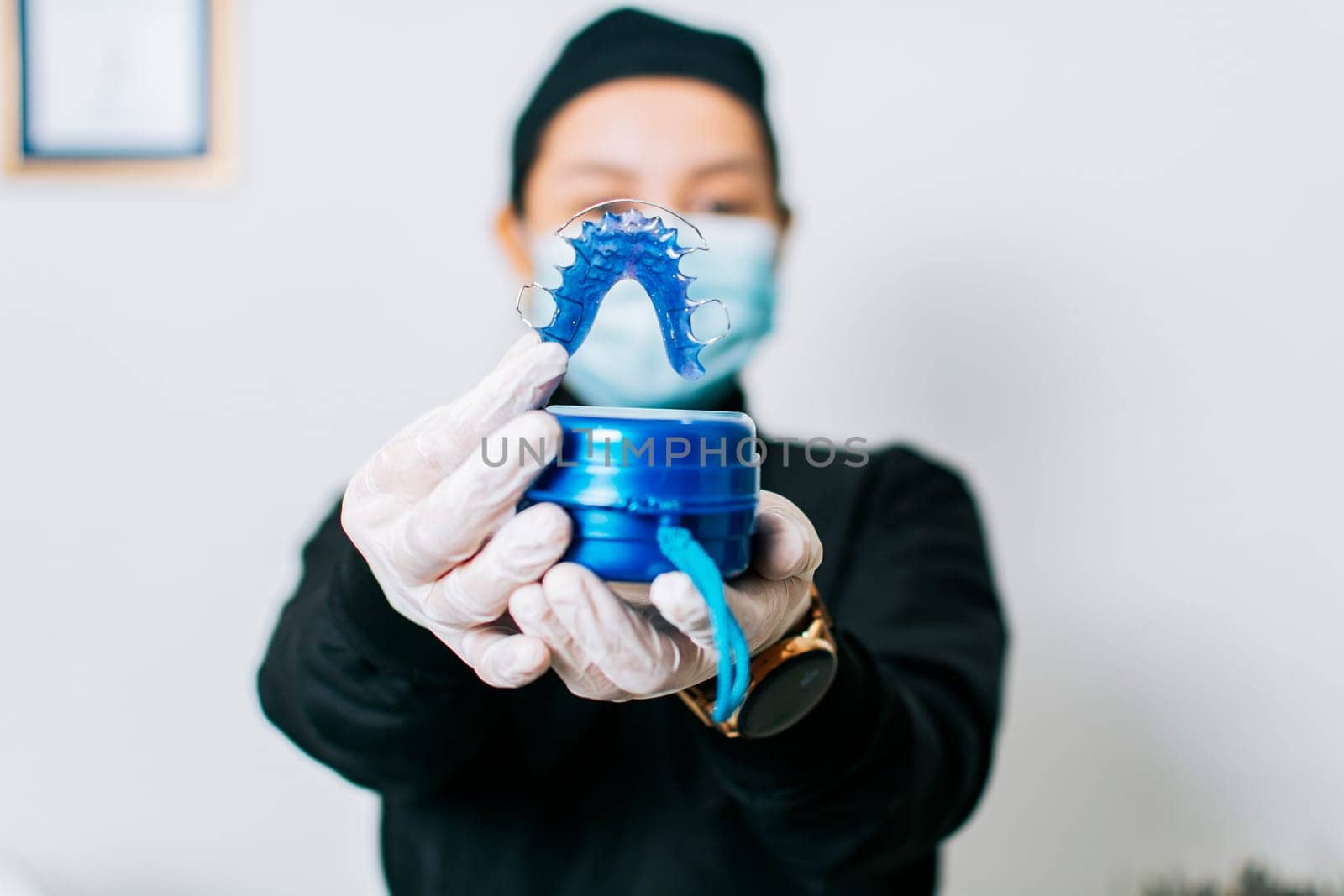 A dentist holding retainers, Female dentist holding dental retainers, Portrait of a female dentist holding retainers
