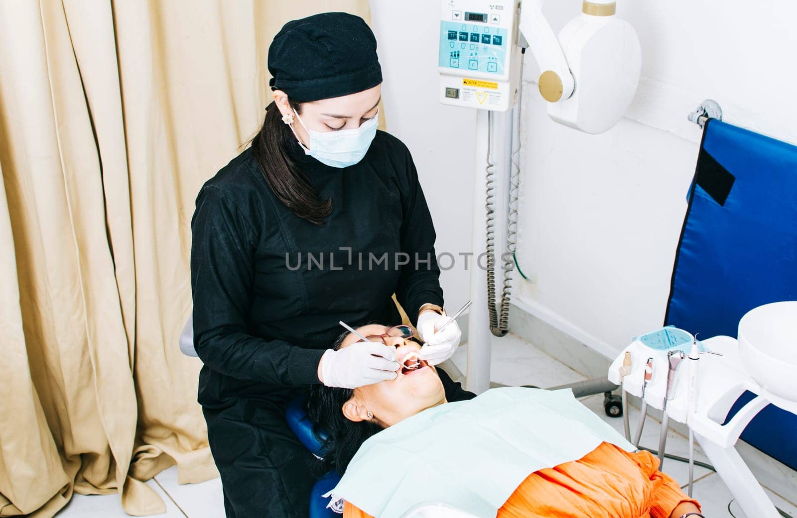 Woman dentist with patient lying down, Dentist examining mouth to patient, Woman dentist doing endodontics to woman patient, Dentist performing stomatology