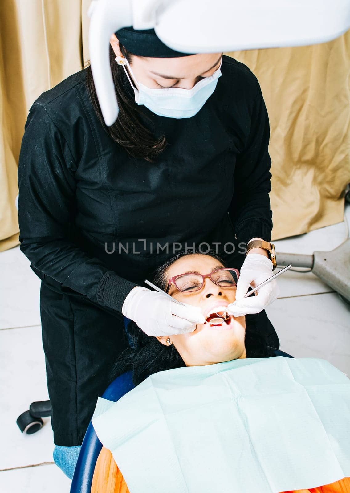 Dentist examining mouth to patient, Woman dentist doing endodontics to woman patient, Woman dentist with patient lying down, Dentist performing stomatology
