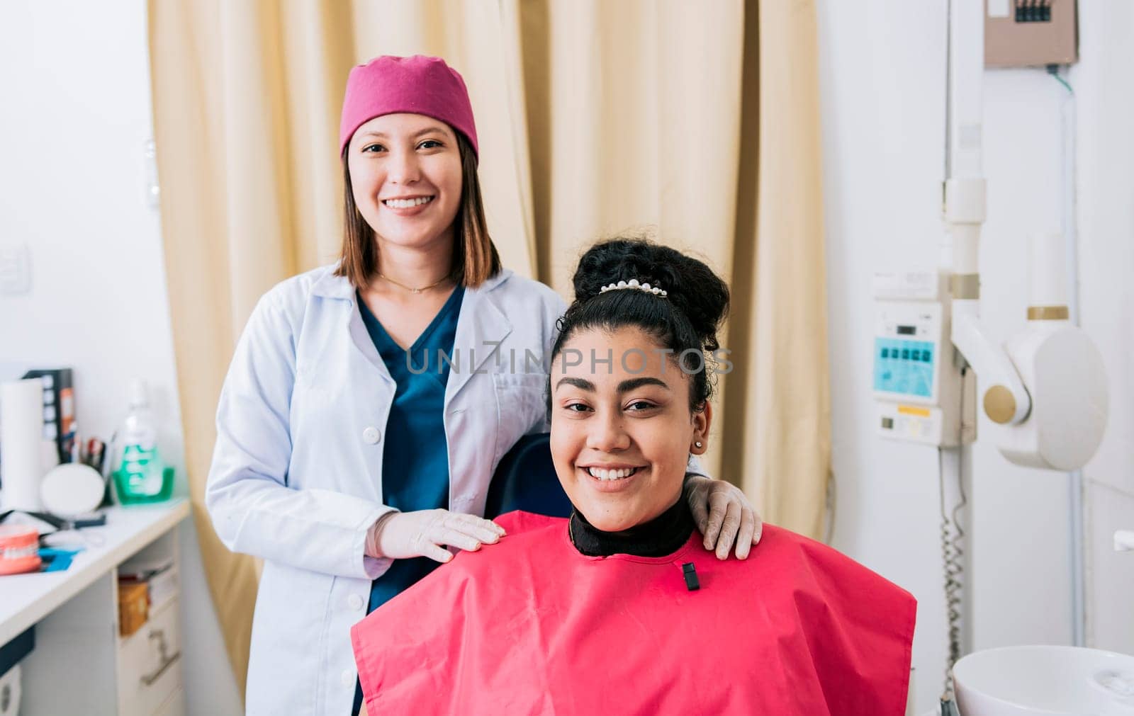 Female dentist with satisfied patient smiling at camera, Female dentist with patient smiling friendly. Portrait of dentist with patient smiling at camera in office