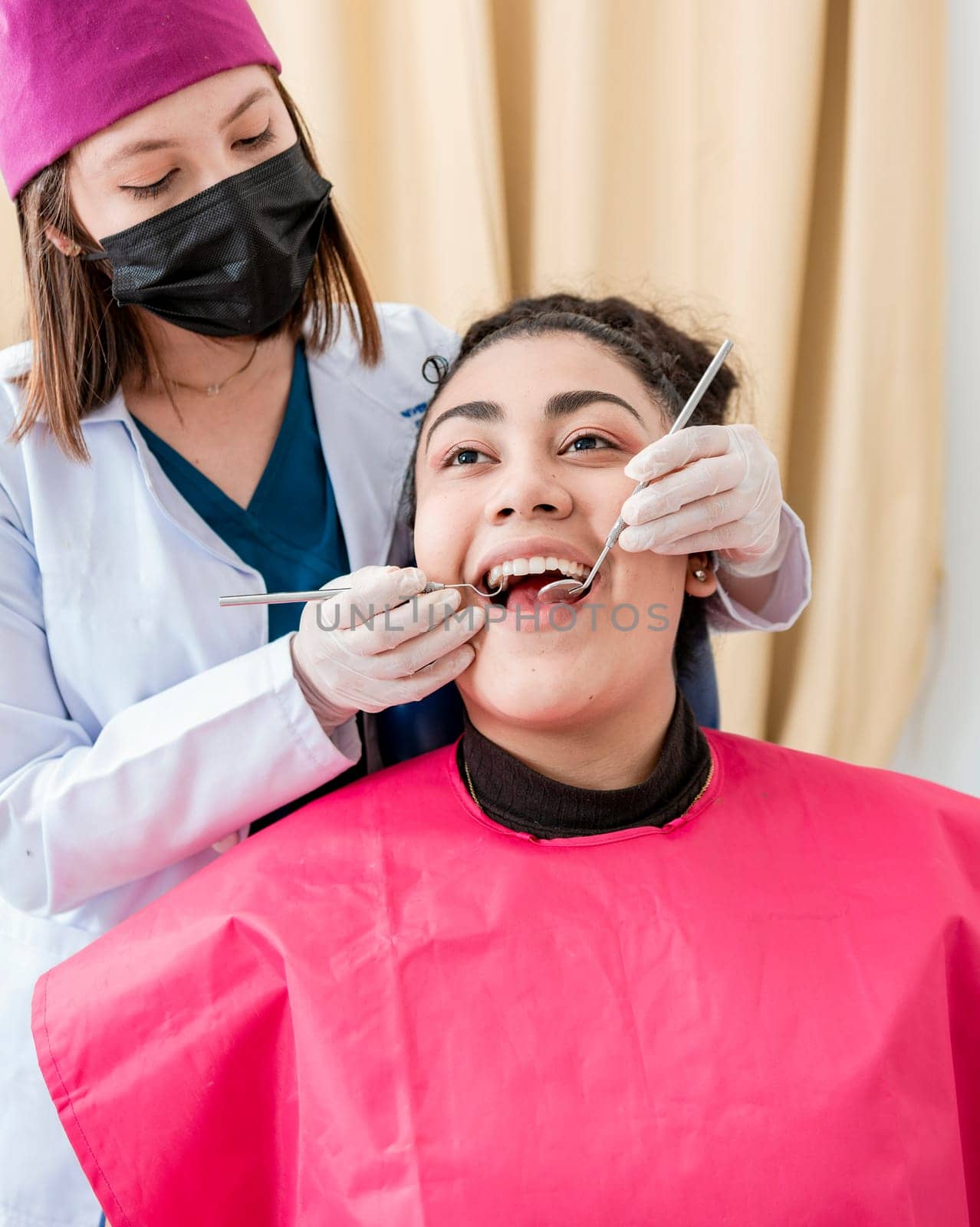 Dentist checking patient with excavator and dental mirror, Front view of dentist checking patient with excavator and dental mirror, Patient checked by dentist, Dentist doing dental checkup
